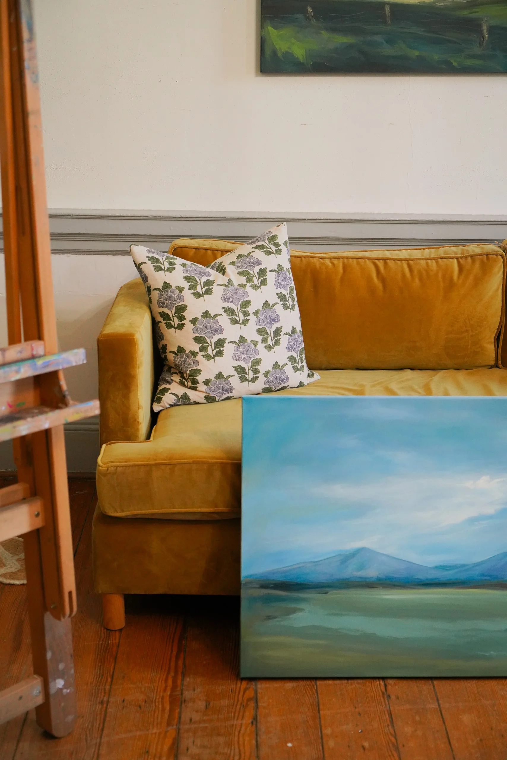 Yellow sofa and a landscape painting in an art studio.